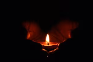 Manos sosteniendo una vela encendida en la oscuridad