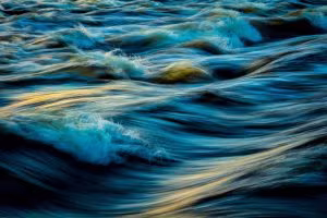 Agua agitada en movimiento con reflejos azules y dorados