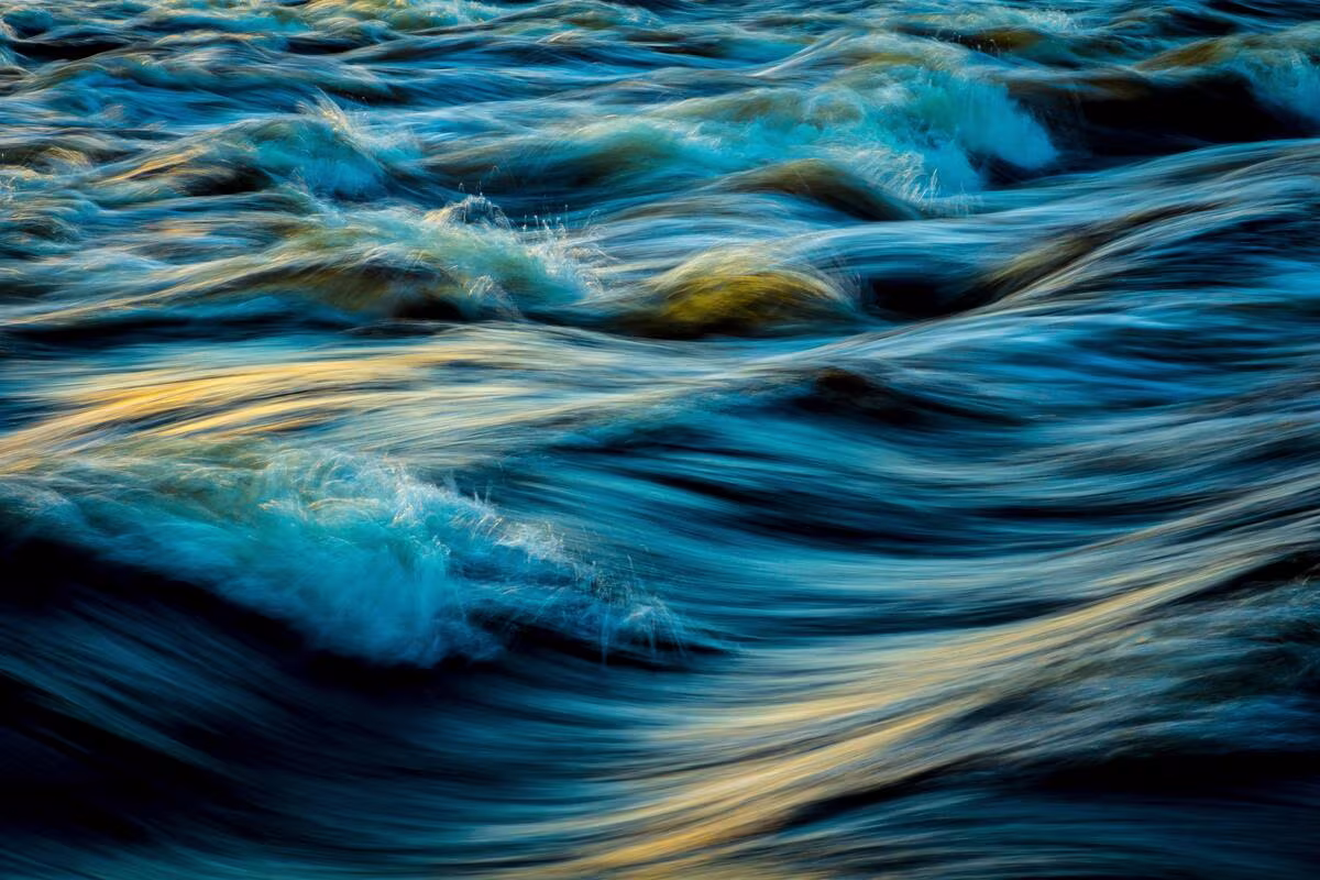 Agua agitada en movimiento con reflejos azules y dorados