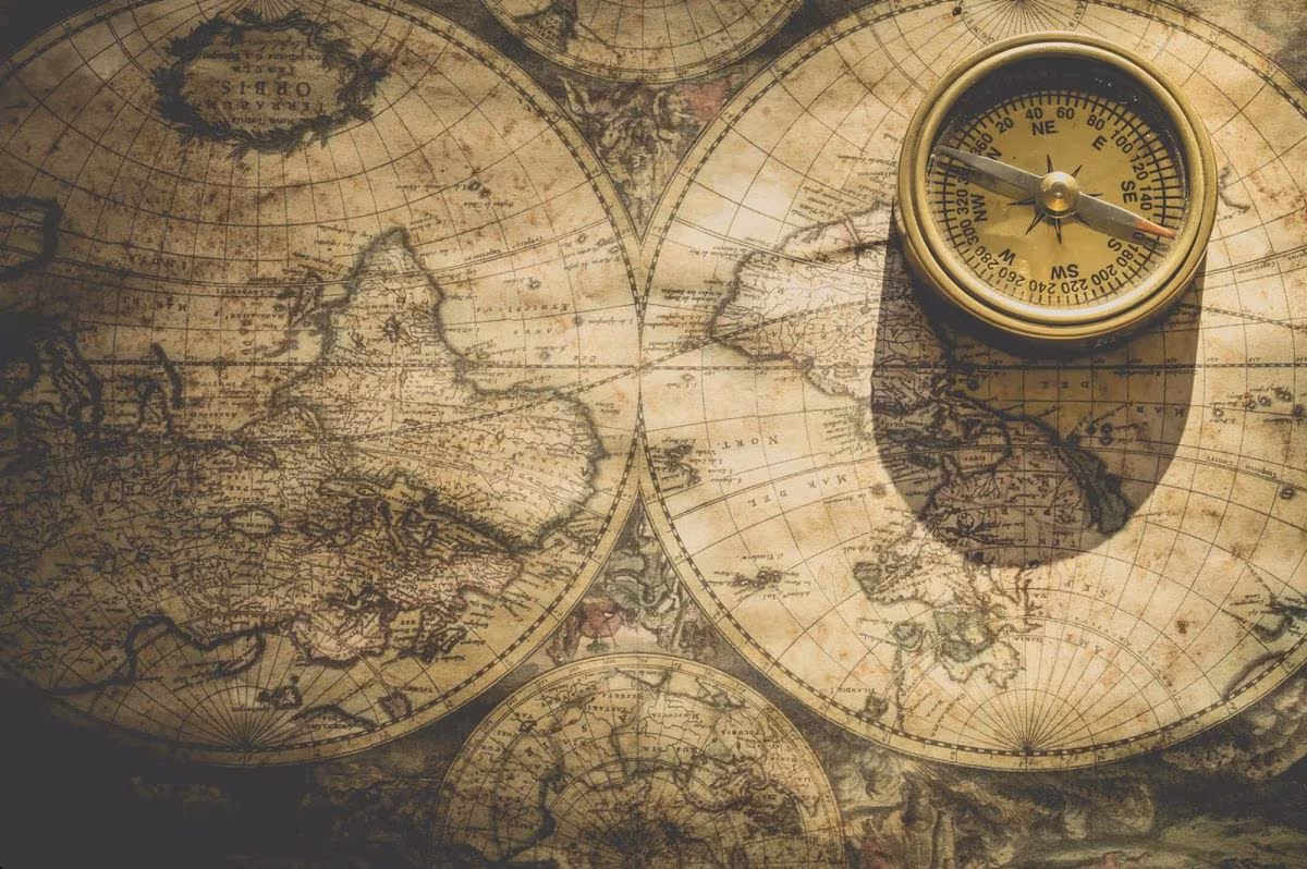 Mapas antiguos del mundo con una brújula de latón encima