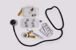 Stéthoscope, pilulier, plaquettes de comprimés et thermomètre sur fond blanc