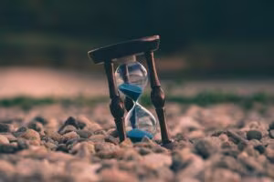 Reloj de arena con arena azul sobre un suelo de piedras
