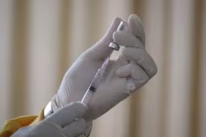 Manos con guantes cargando una jeringa desde un vial