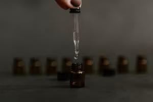 Cuentagotas dejando caer una gota en un frasco de vidrio ámbar