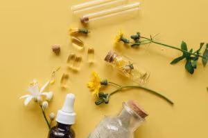 Cápsulas, flores, frascos cuentagotas y tubos de ensayo sobre fondo amarillo