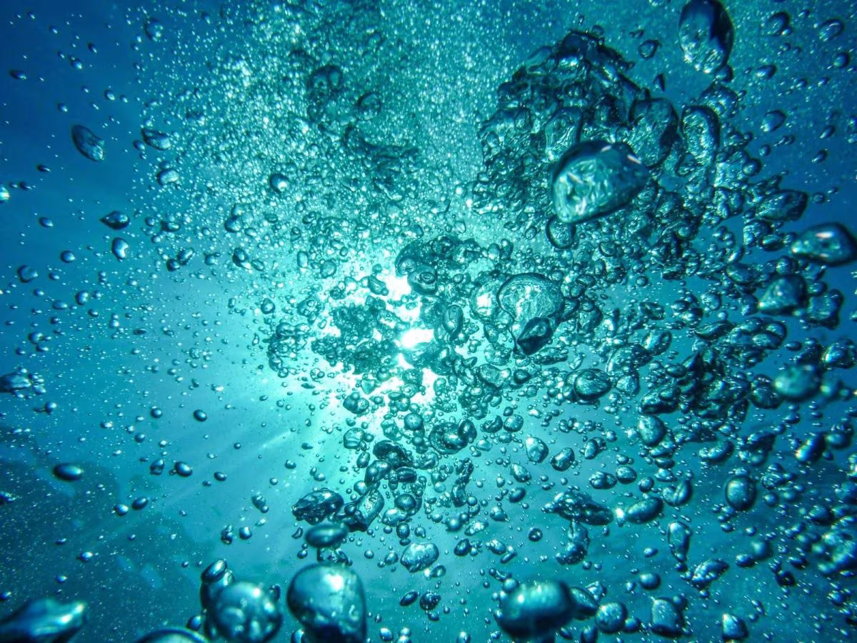 Burbujas bajo el agua iluminadas por la luz del sol