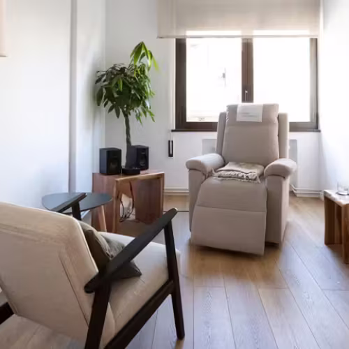 Sala de terapia luminosa con sillón reclinable, planta y altavoces
