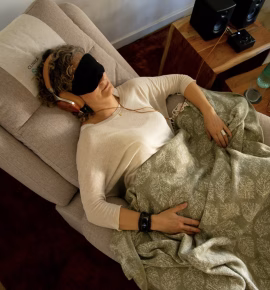 Paciente reclinada con antifaz y auriculares, cubierta con una manta